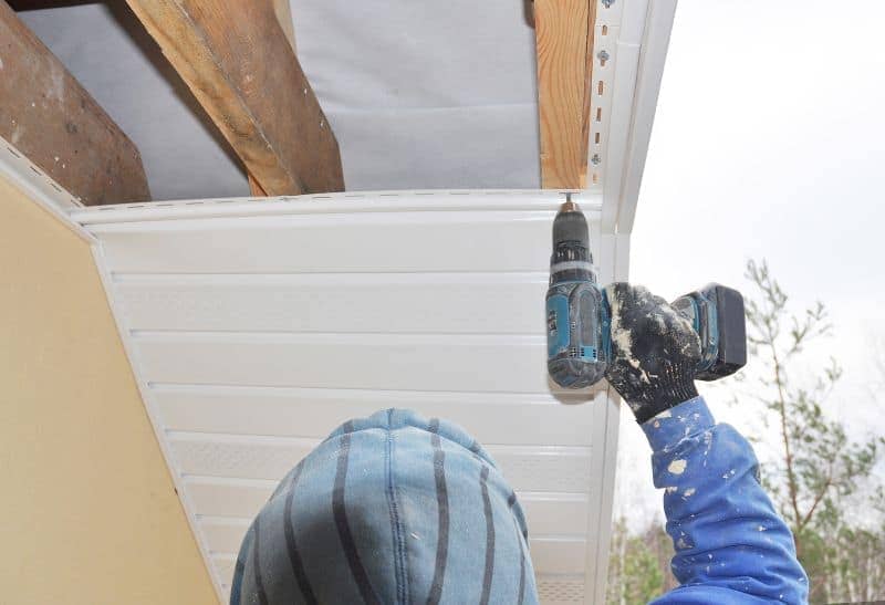 Roofer installing soffit and fascia boards on a house