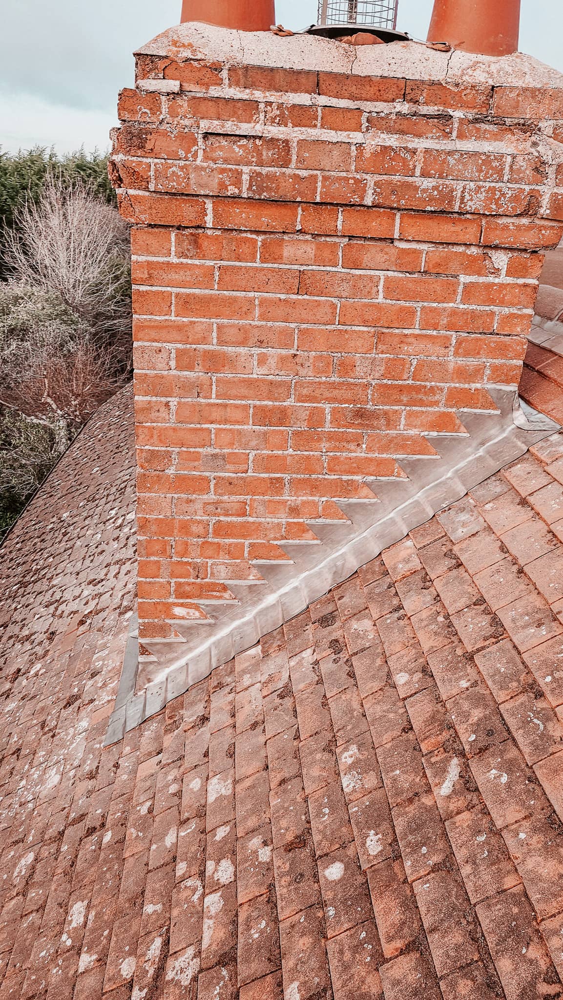 Lead flashing repair at a brick chimney on a tiled roof